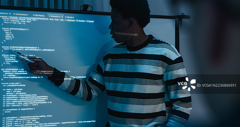 夜间办公室中，来自不同背景的IT专业人士聚焦展示编码和网络安全。人工智能与编程。图片素材