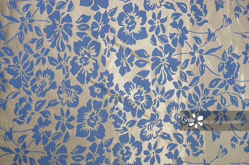 蓝色花卉图案的面料，背景为米色图片素材
