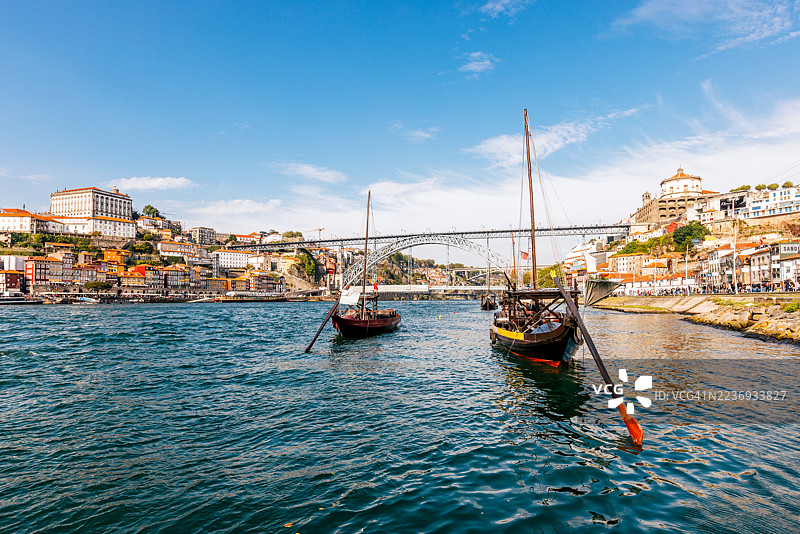 装载波特酒桶的拉贝洛船与阳光明媚的波尔图市景及路易斯一世大桥，葡萄牙波尔图图片素材