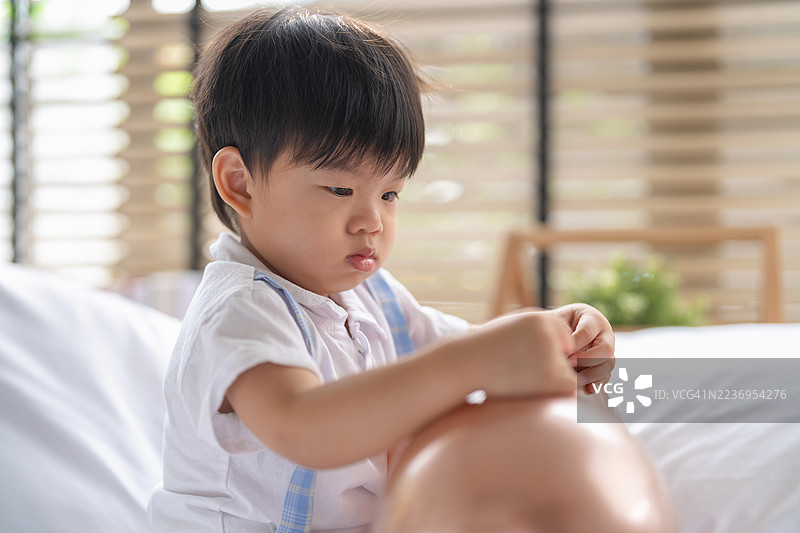 可爱的亚洲幼儿男孩在家中玩耍，手里拿着五颜六色的气球，开心地笑着，享受着快乐的周末早晨活动，展现幸福的童年生活瞬间。图片素材