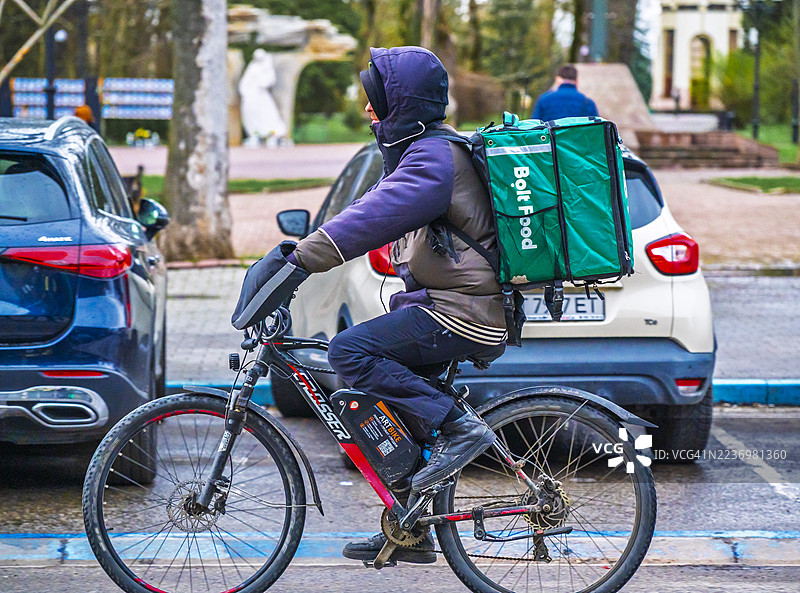 骑自行车在城市街道上送餐的快递员，为一家配送服务公司工作图片素材