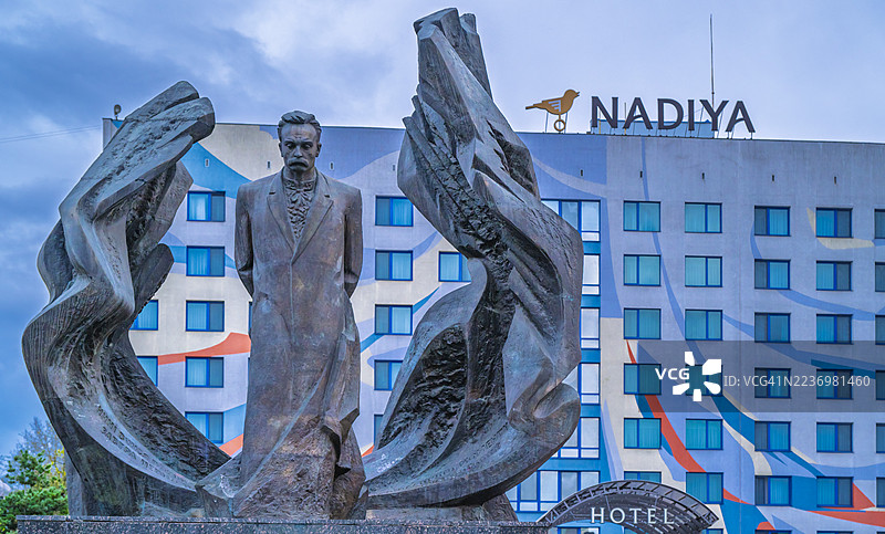 伊万诺-弗兰基夫斯克市中心的作家伊万·弗兰科的青铜纪念碑，历史地标俯瞰着一个公共广场，天空多云。图片素材