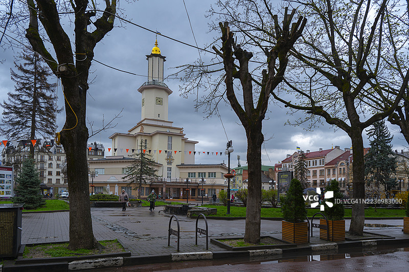 伊万诺-弗兰基夫斯克市政厅矗立在主要市广场上，拥有金色圆顶和钟楼，周围环绕着历史建筑，光秃的树木。图片素材