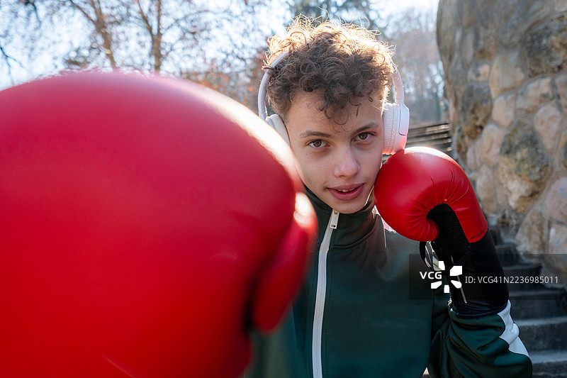 户外训练的少年男孩戴着耳机进行拳击训练图片素材
