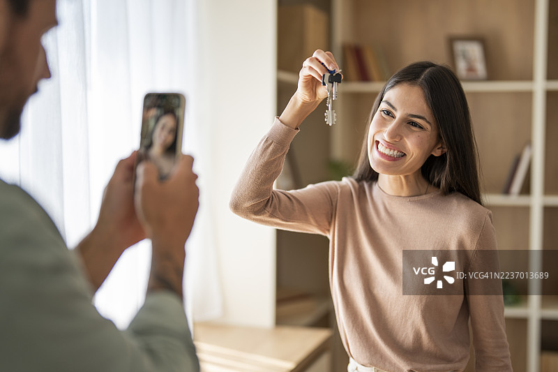 快乐的女人展示新房钥匙，男人在拍照图片素材