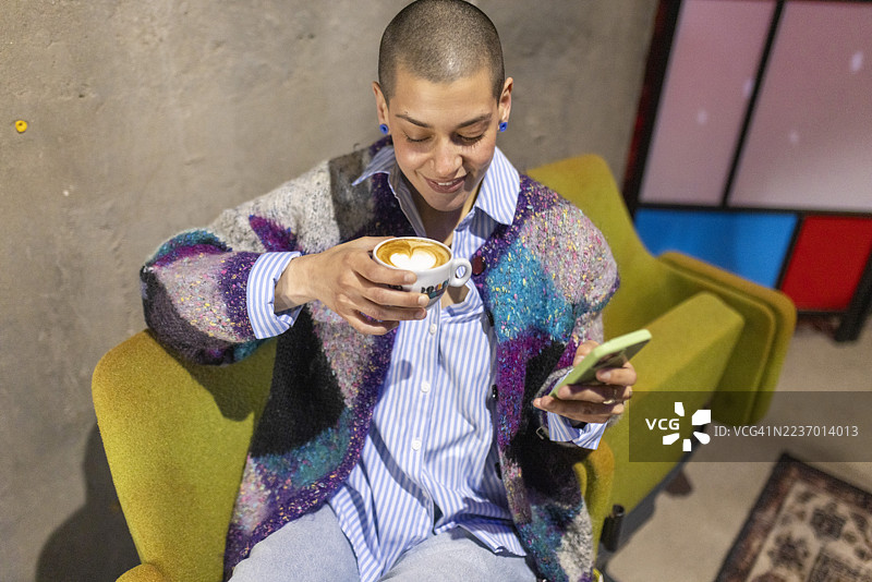 微笑的人在室内享受咖啡和智能手机图片素材