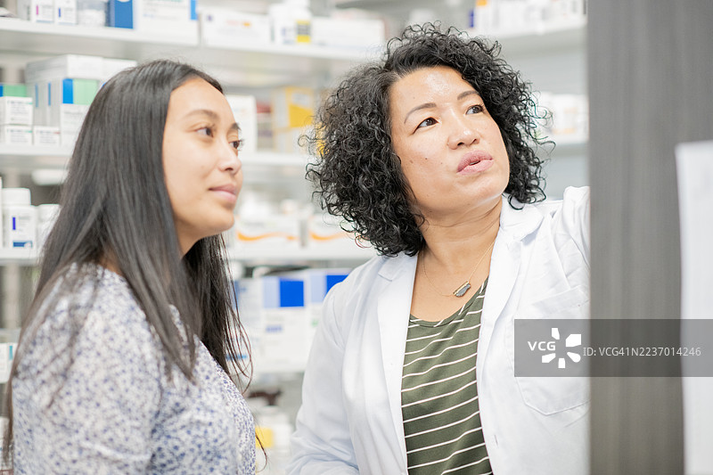药剂师与顾客在现代药房环境中进行友好的咨询会谈，讨论用药选择。图片素材
