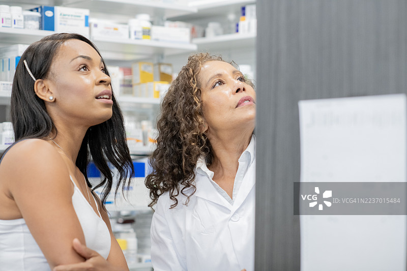 药剂师在药房环境中合作，共同查看监视器进行药物审查和讨论图片素材