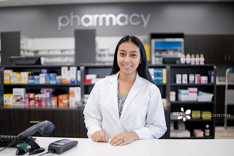友好的亚洲女性药剂师在现代药房柜台提供客户服务图片素材