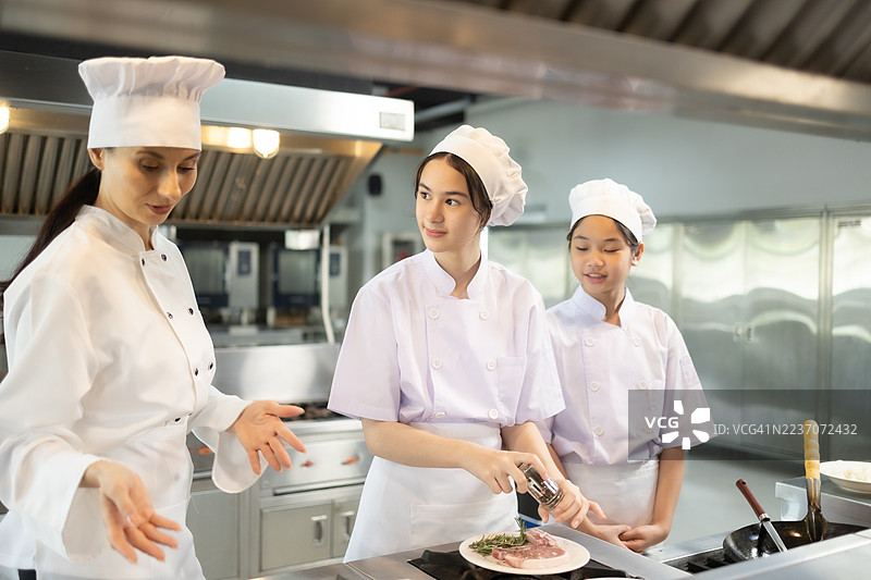少女在食堂厨房做饭。老师和学生们在烹饪课上切菜。图片素材
