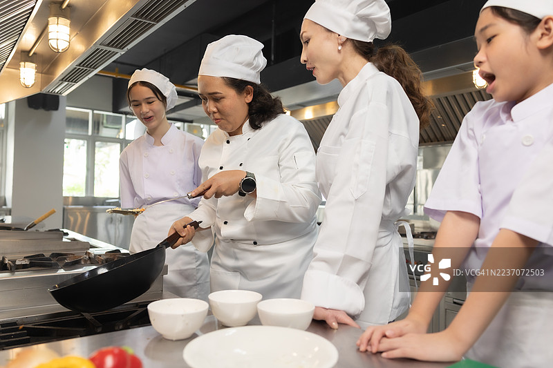 少女在食堂厨房做饭。老师和学生们在烹饪课上切菜。图片素材