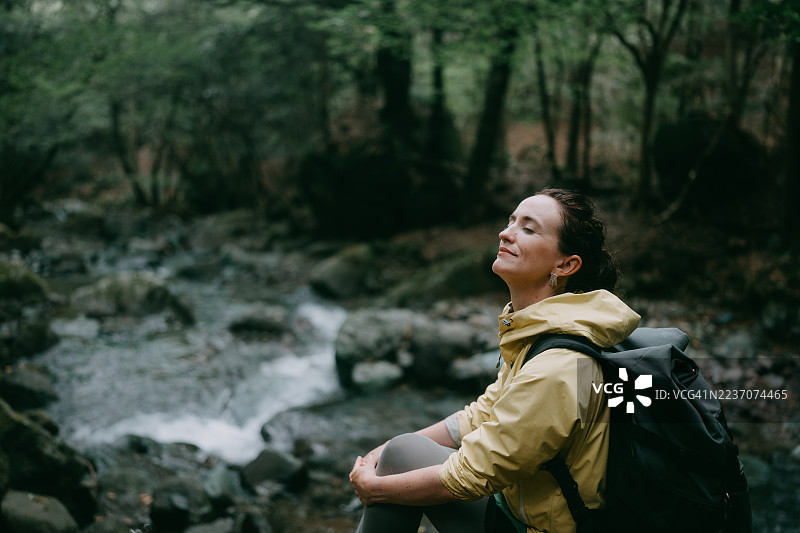 女子在森林徒步时在河边放松图片素材
