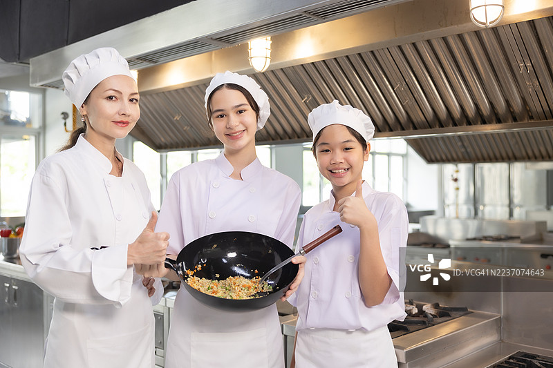 少女在食堂厨房做饭。老师和学生们在烹饪课上切菜。图片素材
