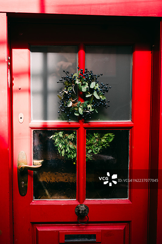 带有花环装饰的亮红色大门营造出节日般的家居入口景象图片素材