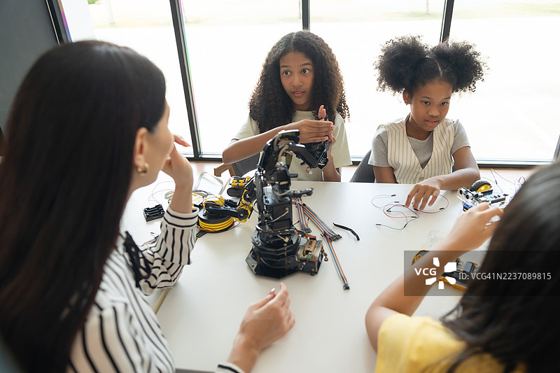 聚焦机器人手臂，孩子们在老师的指导下进行动手STEM活动。多种族学生在机器人课程中与机器人车辆一起学习。图片素材