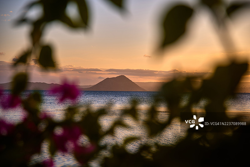宁静的日落映照在巴坦加斯的塔尔湖上，塔尔火山呈锥形矗立。图片素材
