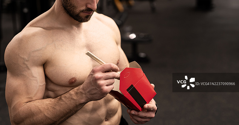 强壮的运动员正在吃一份健康的沙拉。图片素材