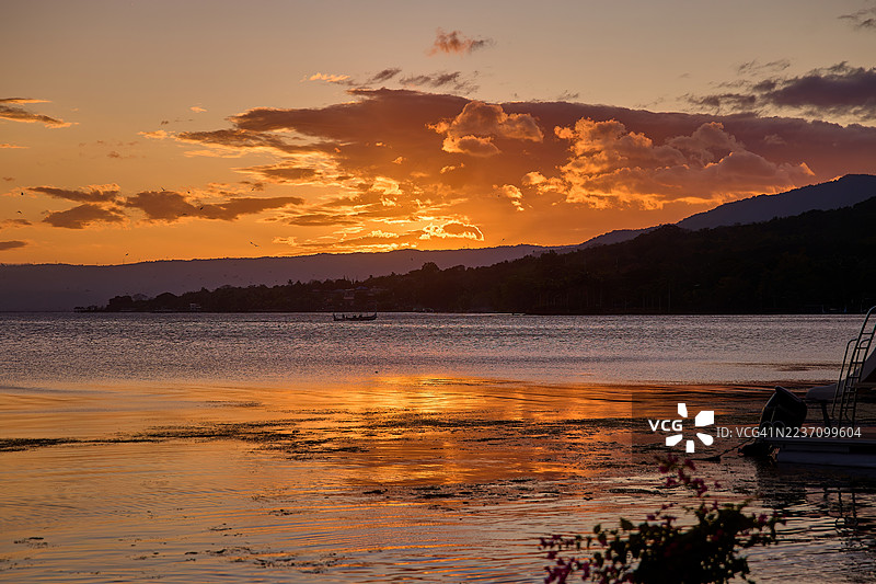 宁静的日落在平静的湖面上投射出鲜艳的橙色和紫色倒影。图片素材