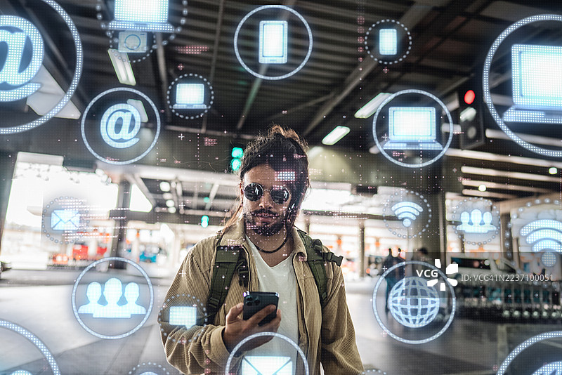 中年男子在机场一边走路一边使用带有未来感数字技术界面的手机图片素材