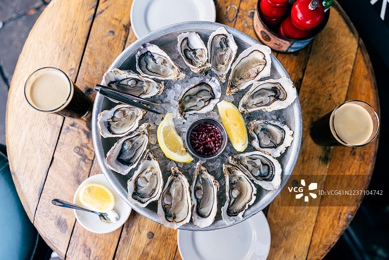 冰上盛放生蚝的托盘和两杯啤酒，置于酒吧的“欢乐时光”期间，俯视图图片素材