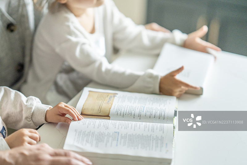 孩子们在白色的桌子前读书：家庭阅读时光与安静的学习时刻图片素材