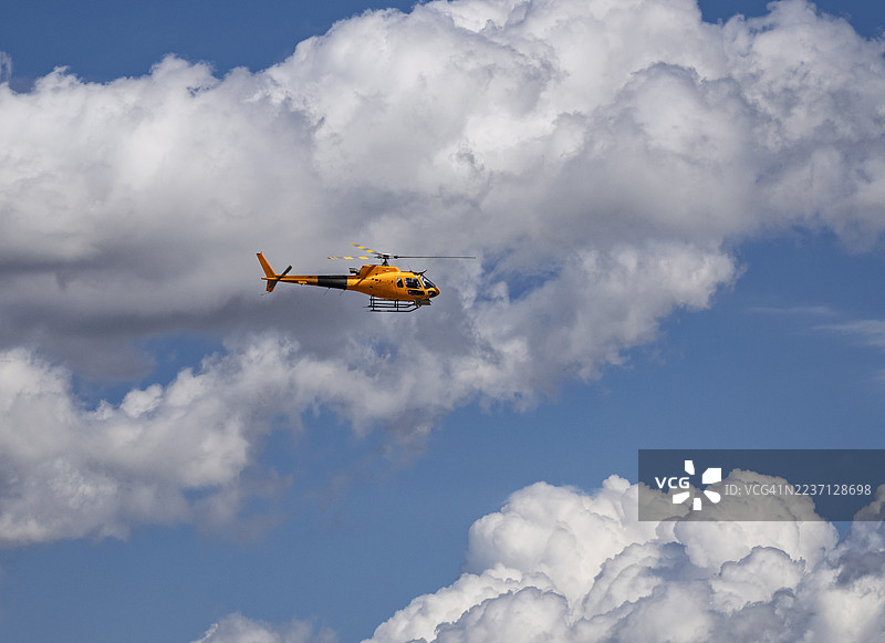 蓝天白云下飞行的直升机。图片素材