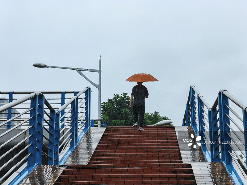 一个男人在雨天走在天桥上图片素材