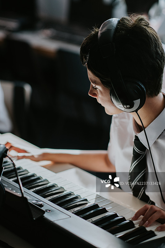 一位另类的年轻音乐学生在教室里弹奏键盘图片素材