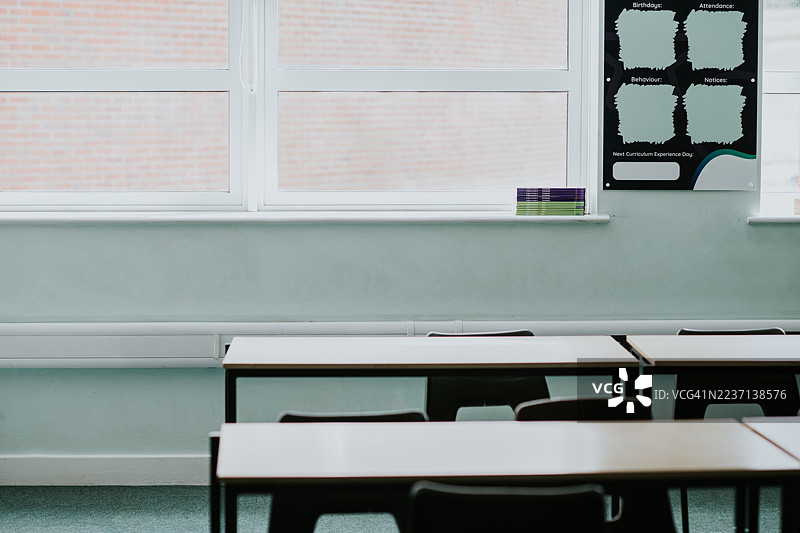 明亮的教室，课桌空着，大窗户在白天让自然光照进来。图片素材