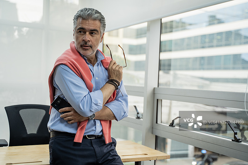 一位沉思的资深行政人员站在办公室窗前图片素材