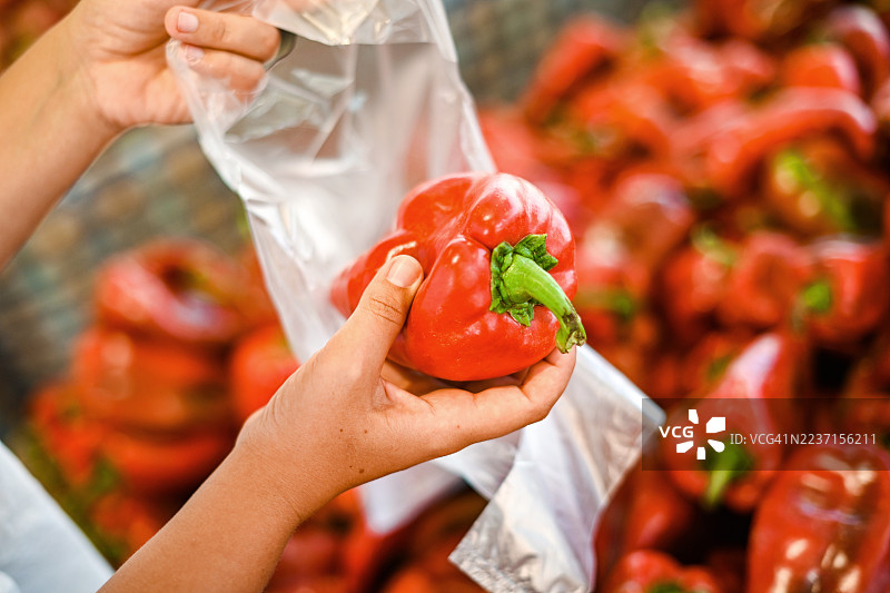 年轻女性在市场上购买新鲜水果和蔬菜（塑料袋）图片素材