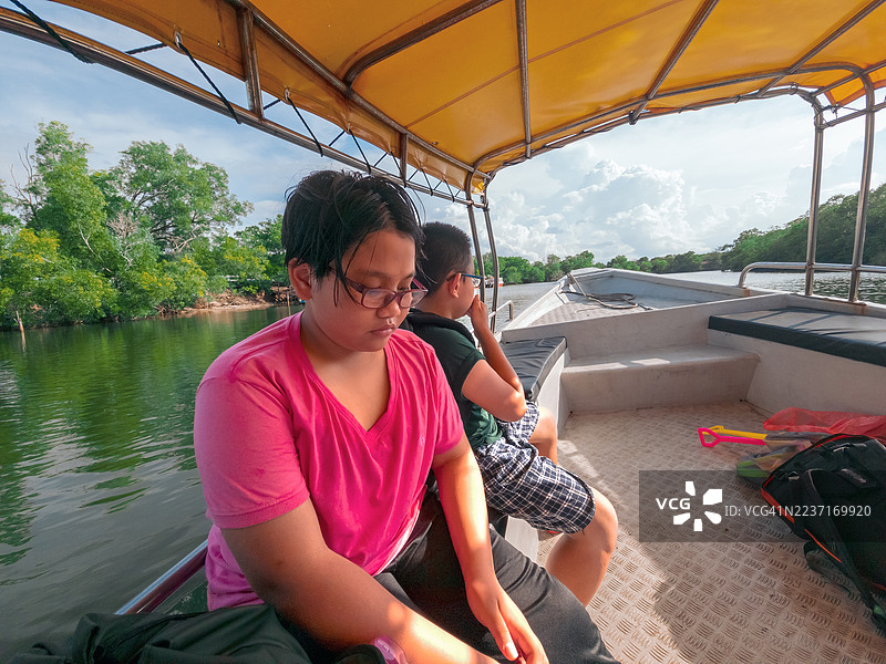 母子俩在绿树环绕的宁静湖面上享受着乘船的乐趣图片素材