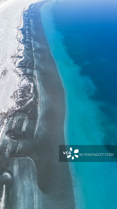 令人惊叹的白色沙滩与生机勃勃的绿松石色和深蓝色海水交汇的航拍景观，形成宁静而自然的抽象图案。图片素材