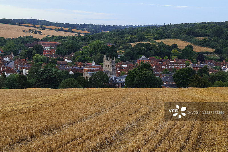 英国阿默舍姆，晴朗天空下，迷人的村庄和连绵起伏的山丘映衬着金色的农田美景，阿默舍姆，英国，英国图片素材