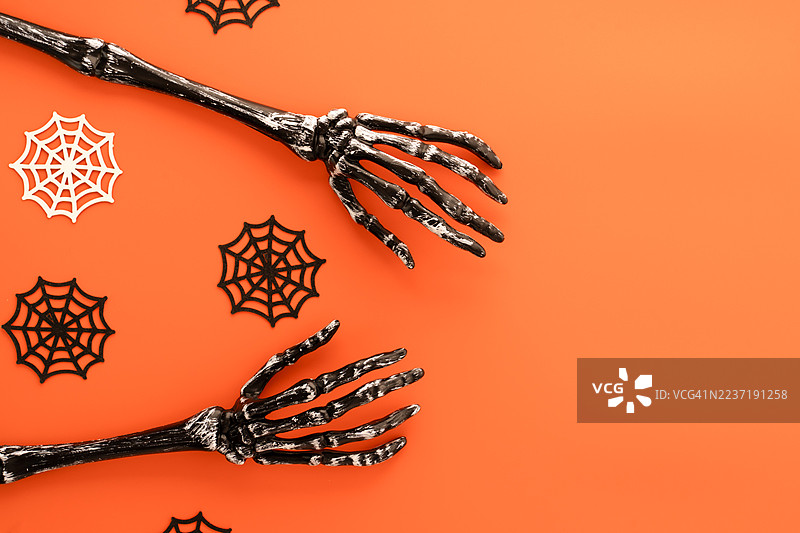 万圣节的骷髅手与橙色背景上的蜘蛛网图片素材
