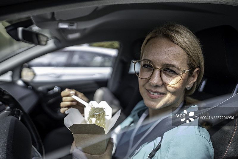 医疗工作者在车里午休时吃外卖面条图片素材