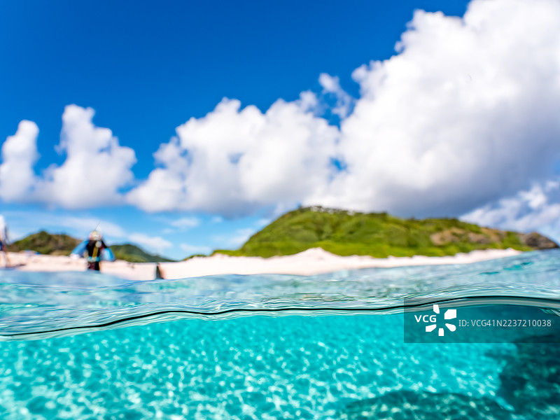 可以看到阳伞、船只，甚至是独特于冲绳的双体船Sabani。拍摄了美丽的白沙滩的一半。还有一群热带鱼。美丽的珊瑚礁和游泳的人们。外岛、座间味岛、慶良間群岛。图片素材