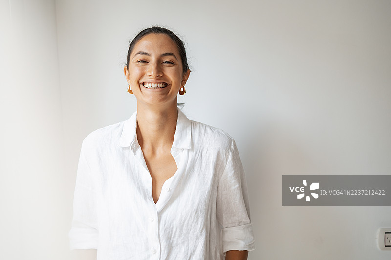 微笑的女性穿着白色衬衫，置身于明亮简约的室内环境中图片素材
