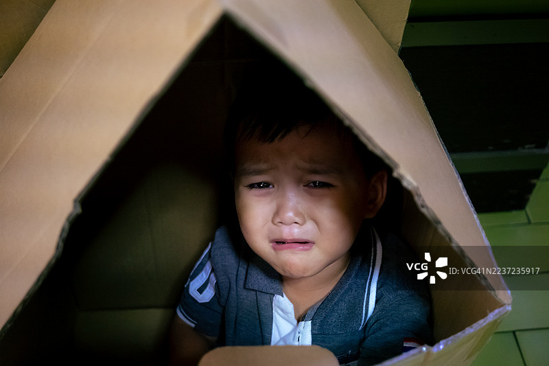 一个男婴坐在纸箱包装内哭泣，表情惊恐图片素材