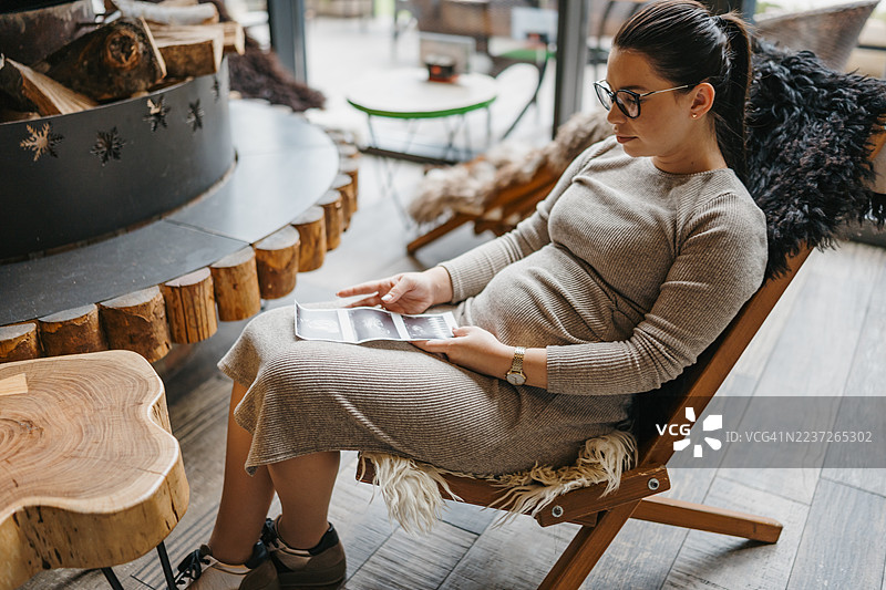 孕妇在家中休息，手中拿着超声波图像图片素材