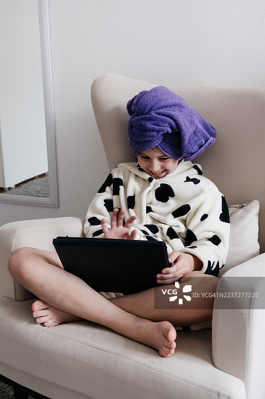 美丽的女孩在家洗澡后使用平板电脑。图片素材