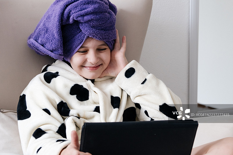 美丽的女孩在家洗澡后使用平板电脑。图片素材