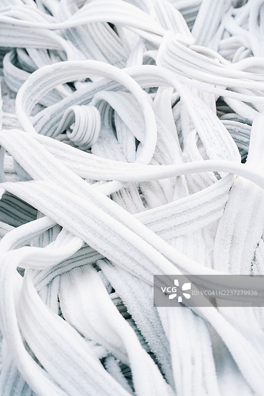 覆盖着一层细霜或雪的波浪形电线或管道特写。图片素材