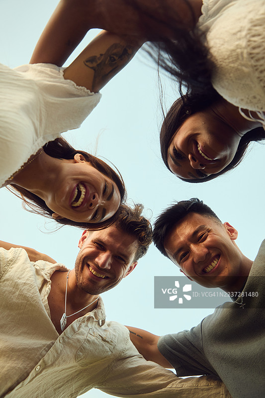 一群朋友在阳光明媚的户外围成一圈，对着镜头微笑图片素材