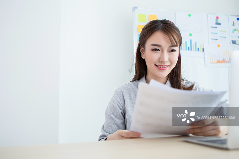 女性坐在办公桌前阅读文件图片素材