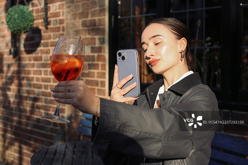 女子用智能手机拍摄鸡尾酒照片图片素材