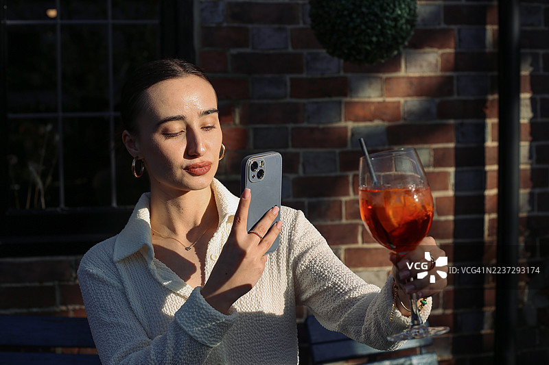女士用智能手机拍摄鸡尾酒照片图片素材