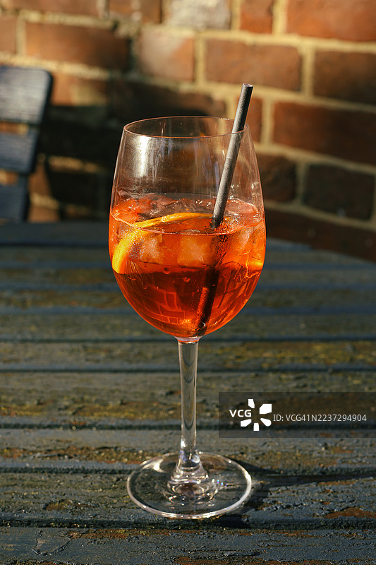 户外冰镇橙色鸡尾酒杯，配有冰块和吸管图片素材