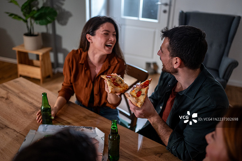 朋友们在家聚会上享用比萨和啤酒图片素材