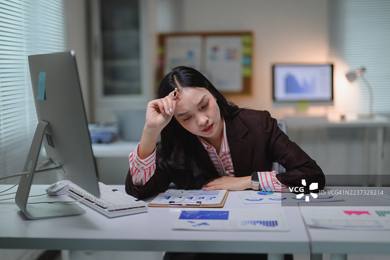 疲惫的女商人在办公室加班，感到压力和过度劳累，遭受职业倦怠和紧迫的截止日期。图片素材